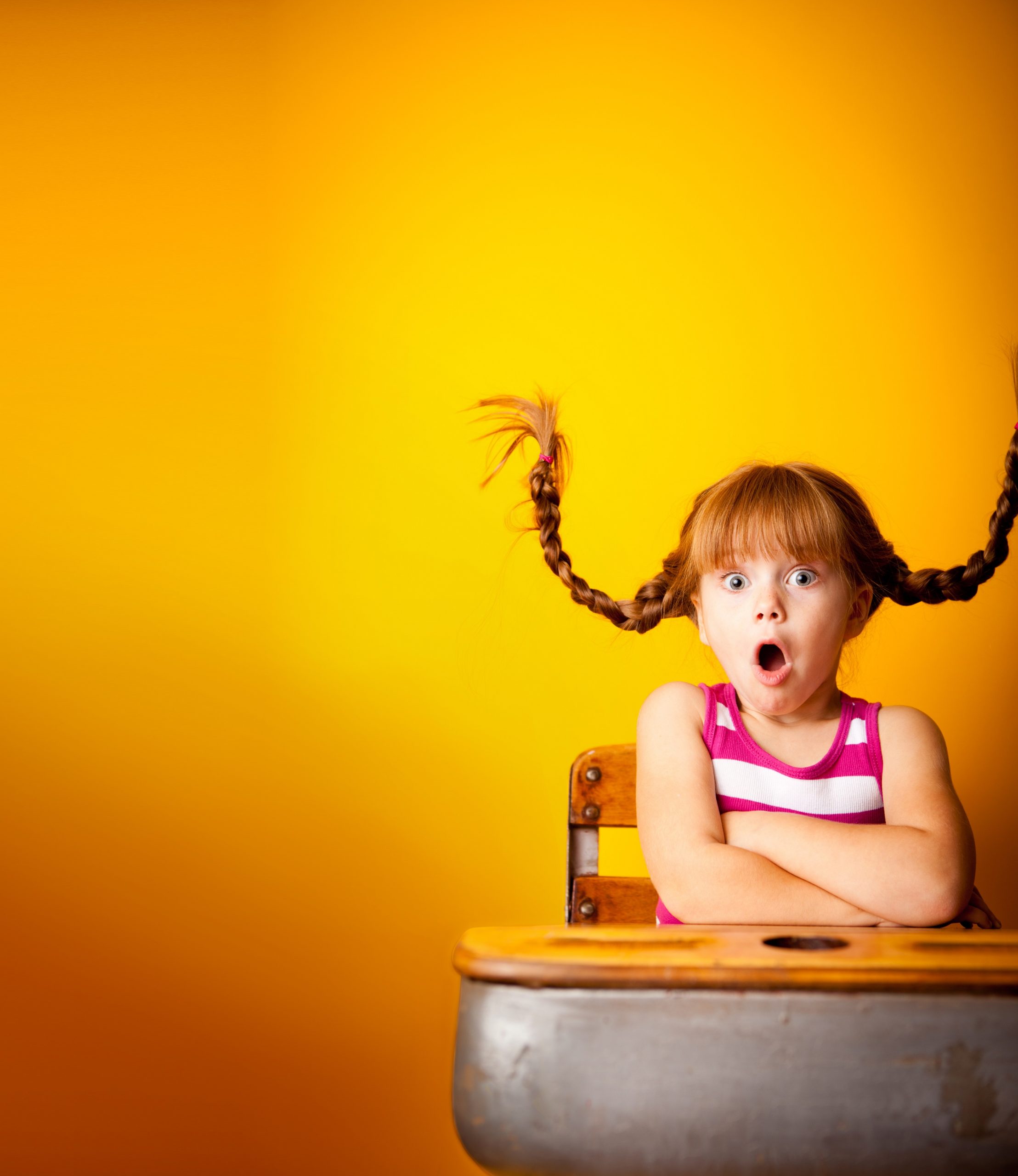 Young girl at desk with wild pigtails