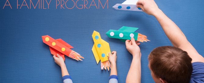 Father and little son are playing with rocket made of paper in the home. Cheerful time together at home. preschool Child in creativity in the home.